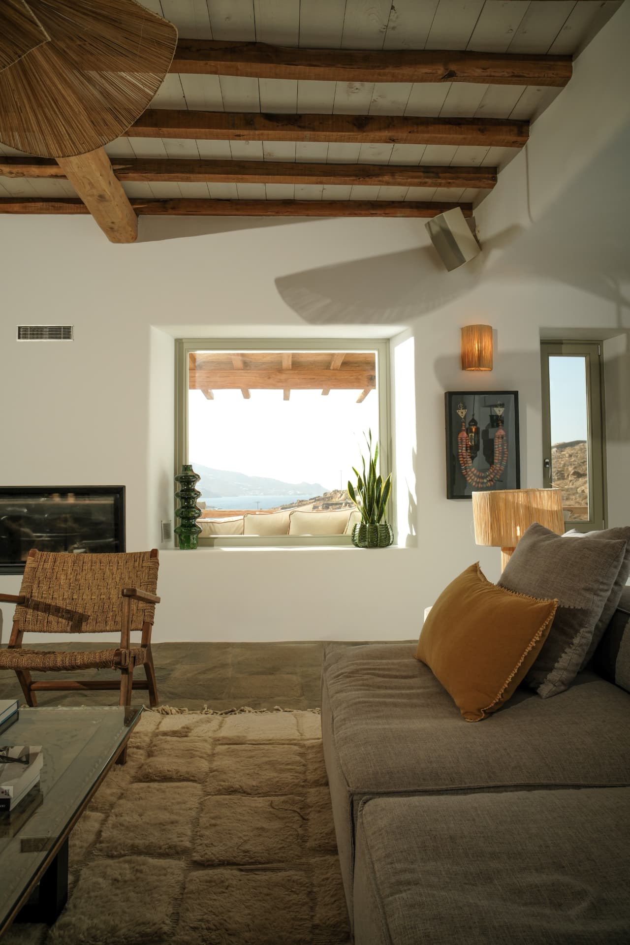 The Living room, woven armchair and window framing the terrace and sea
