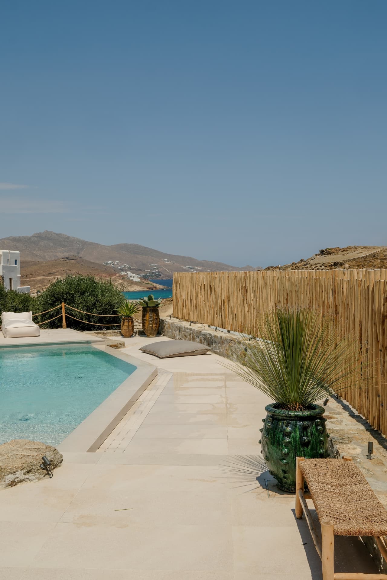 Elevated view of the pool terrace, ceramic planters and the sea in the distance