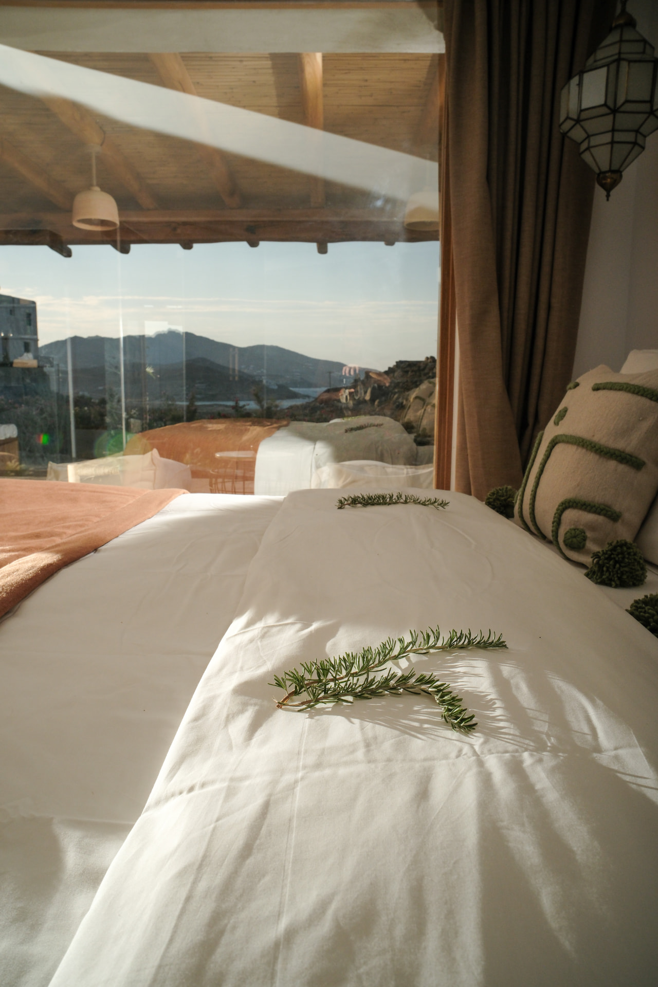 The bed of the Hammam Guest House, warm light across linens and rosemary sprigs