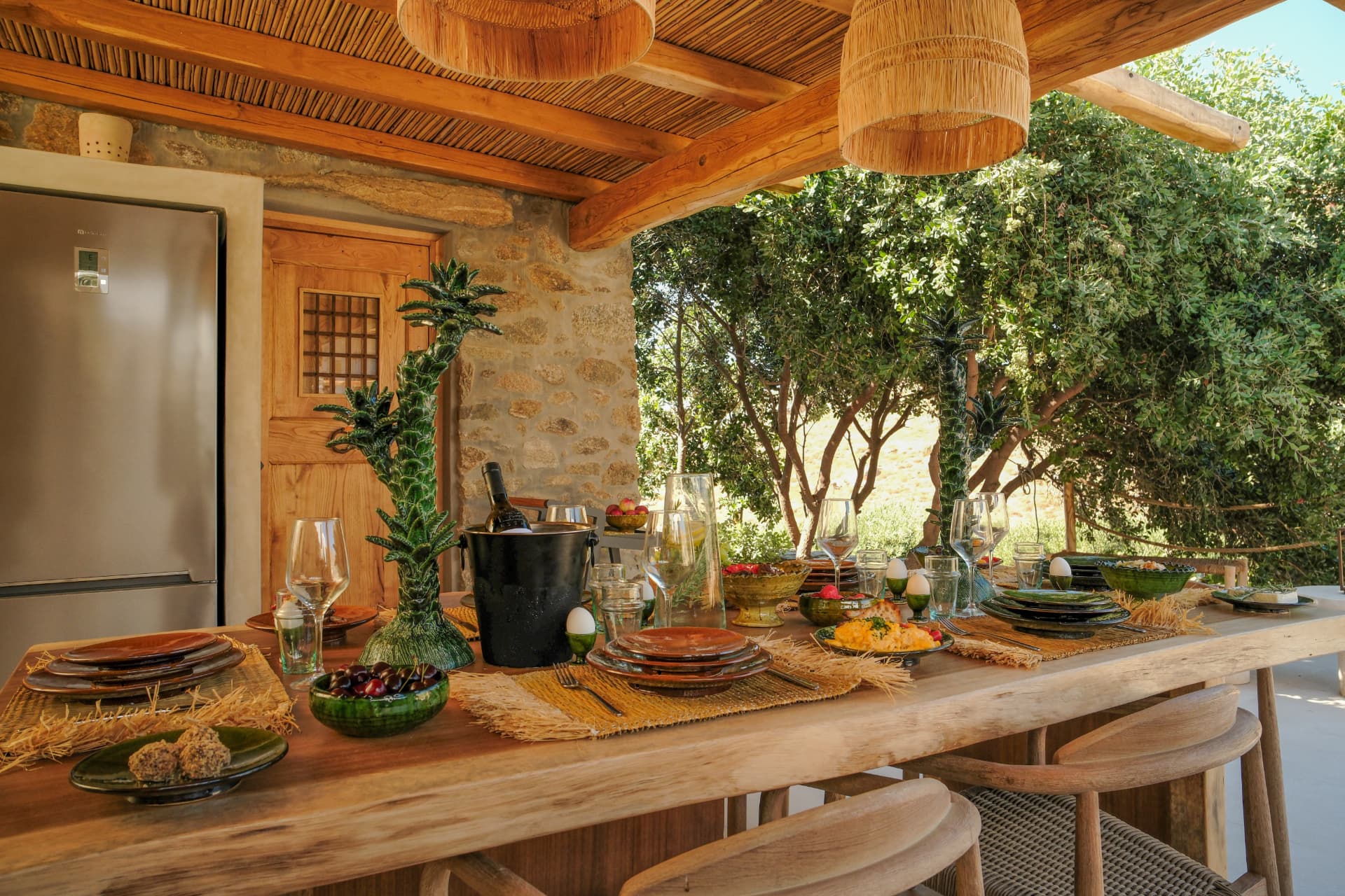 A rustic table set for a meal under the pergola of Villa Storia