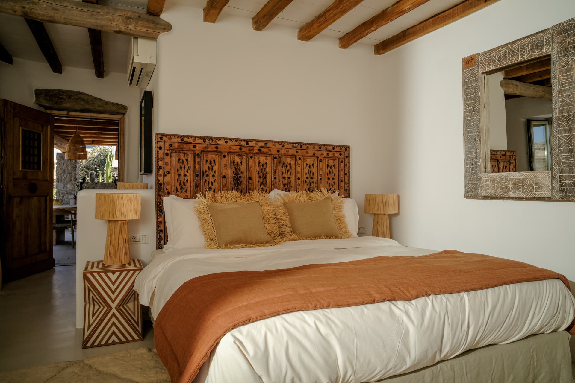 The stone bedroom, carved headboard and terracotta throw in warm light