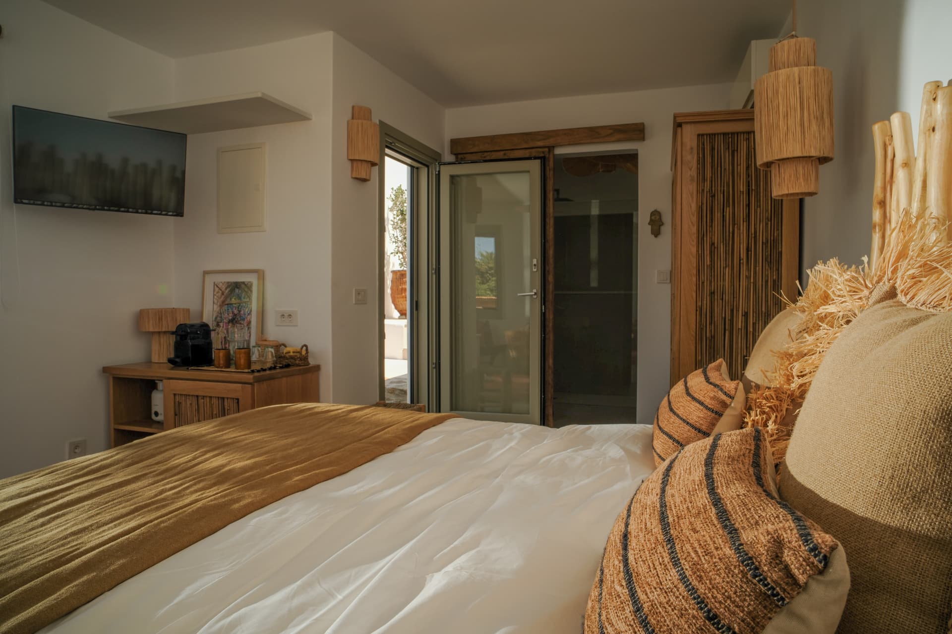 The Cycladic Suite bedroom seen toward the entrance, dresser and open door