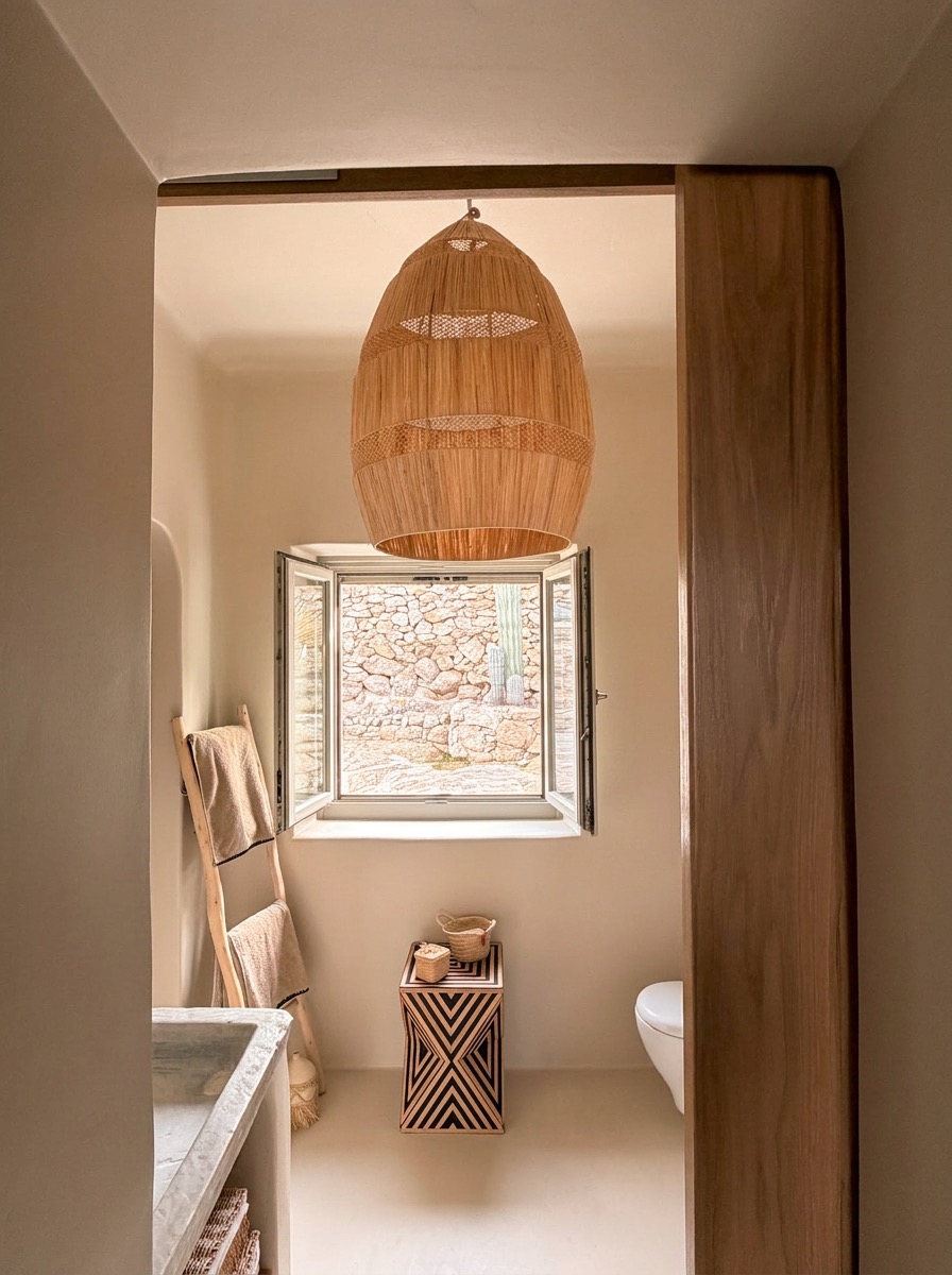 Morning light through the open bathroom window of the Upper Suite, raffia pendant and stone surfaces