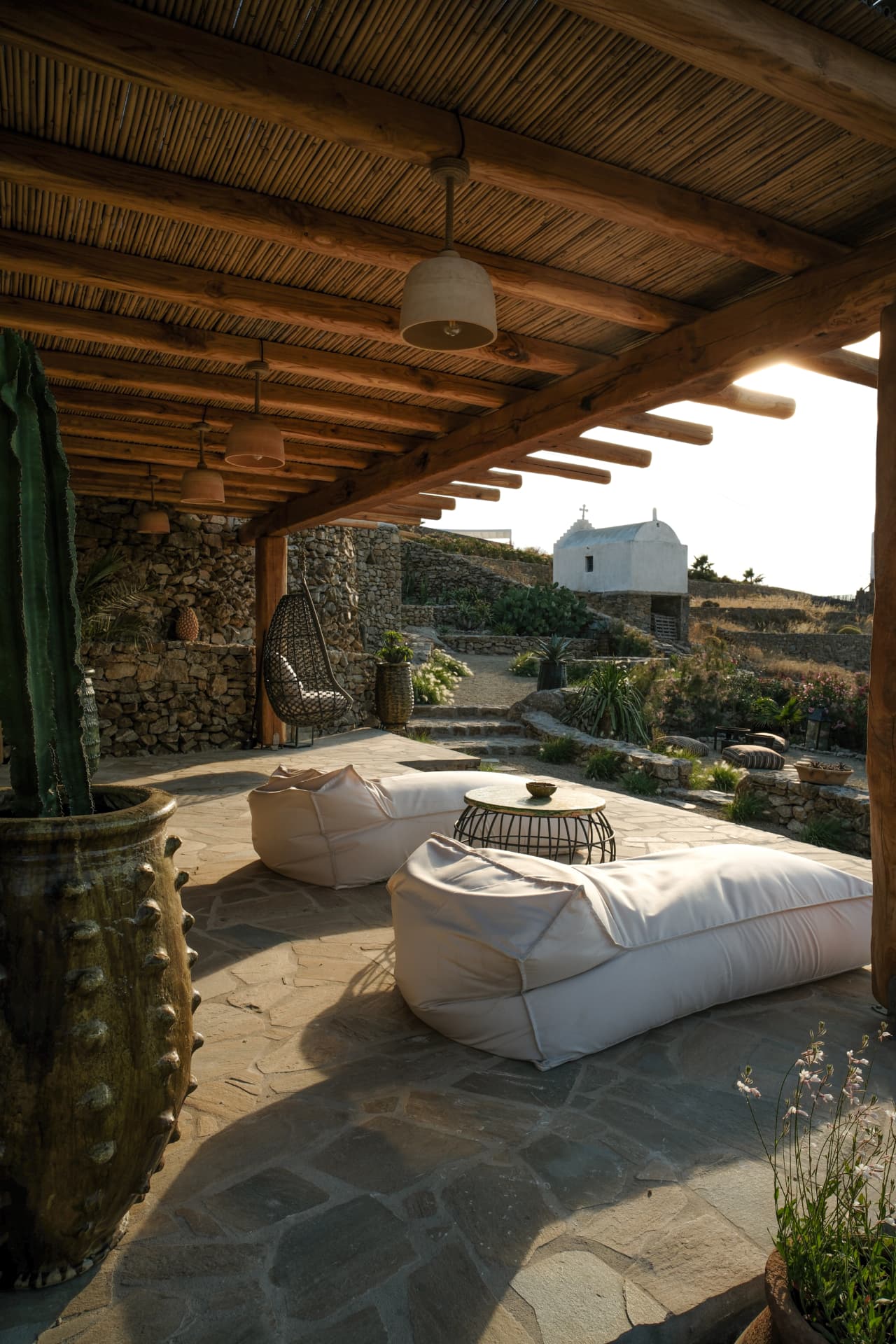 The private terrace of the Hammam Guest House, stone floor, loungers and a white chapel beyond
