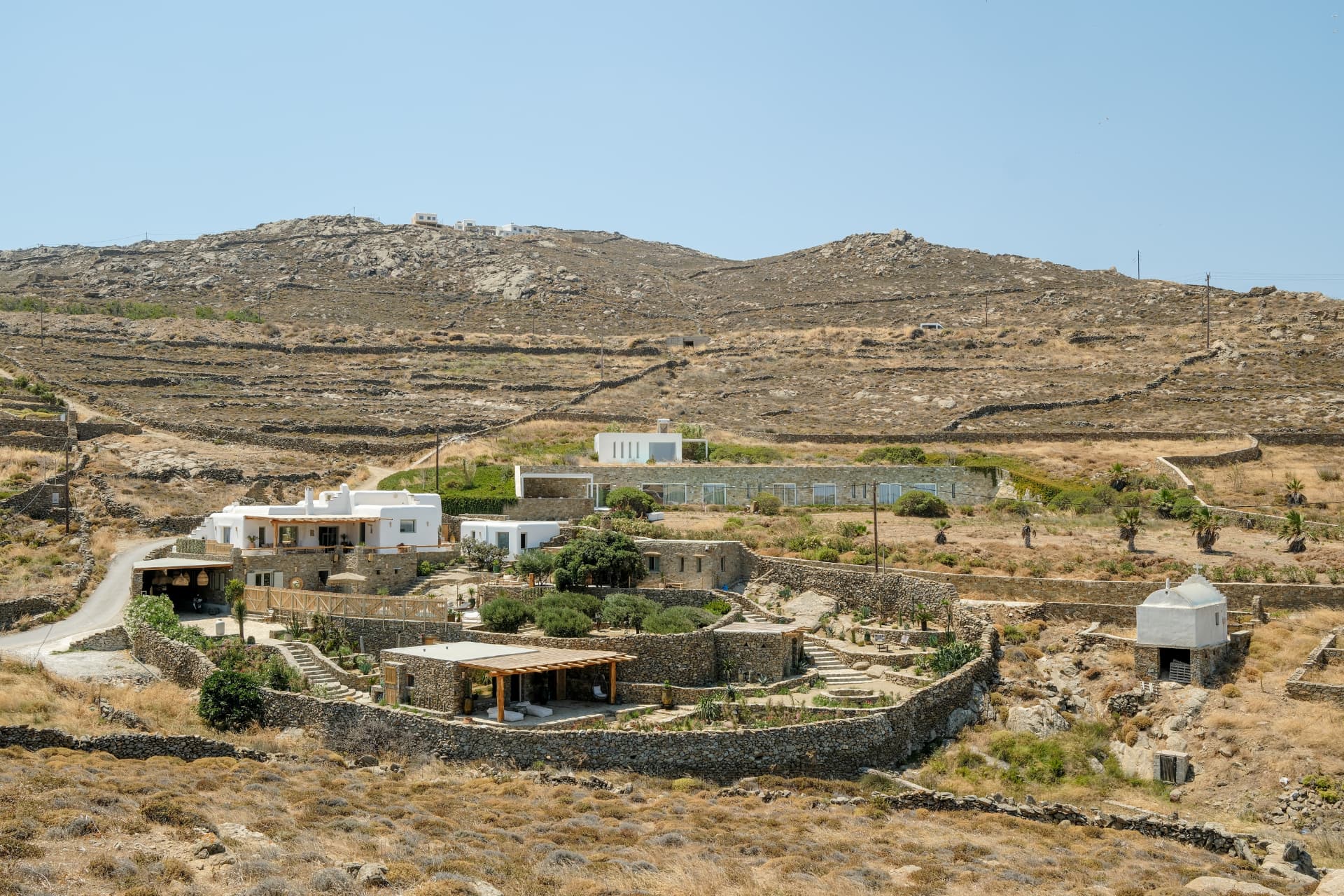 Villa Storia nested within the terraced, dry-stone-walled valley of Ftelia, with a small white chapel nearby