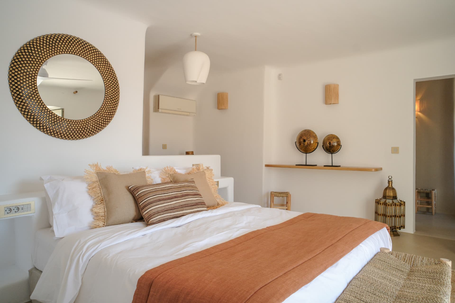 The Master Suite bed, warm light and round mirror above the headboard